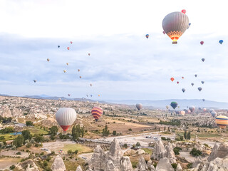 Flying in sky many bright colored beautiful balloons into air in Cappadocia in mountains early at...