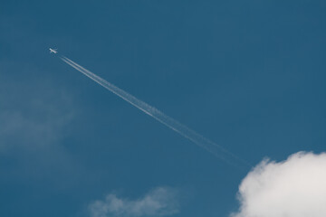 Samolot wysoko na niebie wśród chmur. - obrazy, fototapety, plakaty