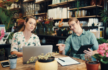 We are always coming up with ways to improve. two young businesspeople sitting and working on technology during a discussion in their floristry.