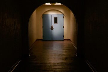 Blue door illuminated at the end of long dark hallway