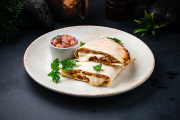 Flatbread with stuffing, sauce, tomatoes, onions, parsley and ham with fresh vegetable salad in a plate.