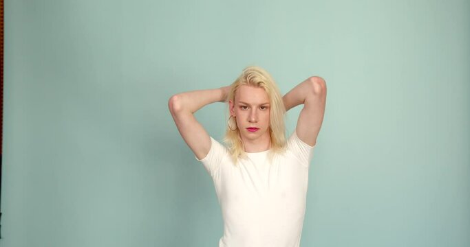 Young serious gay man in casual top isolated on blue color background