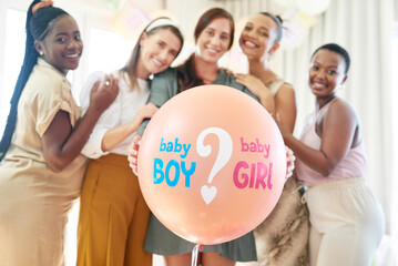 Party games are always fun. a group of women about to pop a balloon for a gender reveal during a...