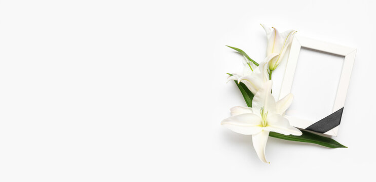 Blank funeral frame and lily flowers on white background with space for text