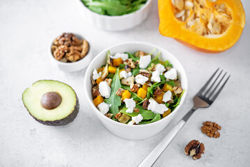 Roasted pumpkin avocado arugula goat cheese salad in a plate