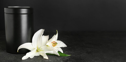 Mortuary urn and white lily flowers on dark background with space for text