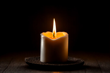 Small burning candle dark background