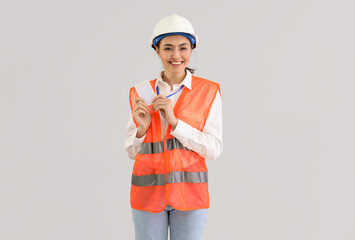 Female worker in vest and with badge on light background