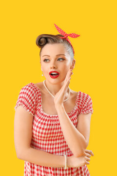 Shocked young pin-up woman on yellow background