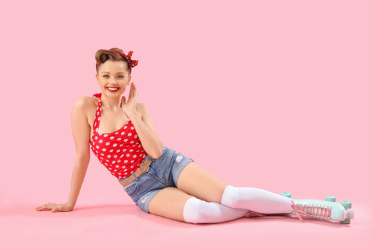 Young pin-up woman in roller skates on pink background