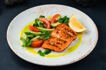 Fried salmon fillet with vegetable salad of avocado, tomatoes and parsley.