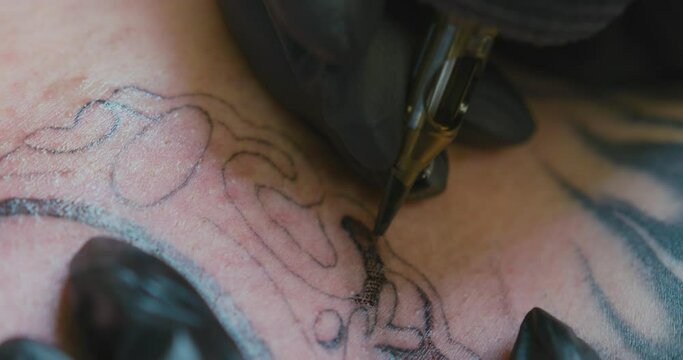 Extreme close-up of the needle of a tattoo machine, tattooing the chest of a white man with the dotwork technique