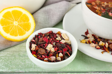 Bowl with dried fruit tea and lemon on green wooden table, closeup