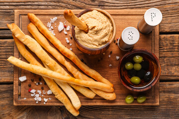 Bowl with tasty hummus and Italian Grissini on wooden background