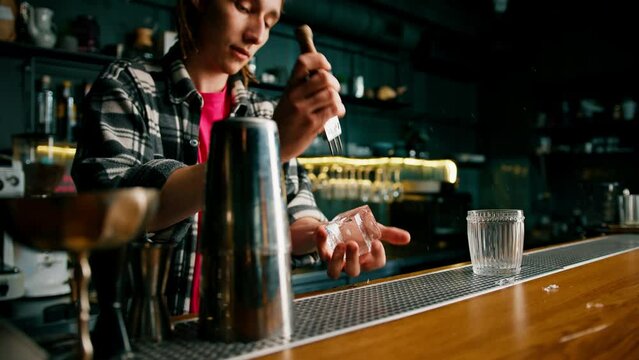 The bartender breaks the ice Close-up of male hands cracking ice with a sharp tool in a bar