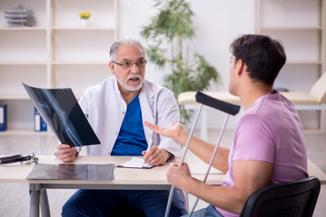 Young leg injured patient visiting old male doctor radiologist