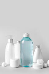 Micellar water with cosmetic products, cotton balls and pads on light background