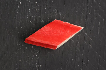 Piece of tasty crab stick on dark wooden background, closeup © Pixel-Shot