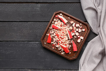 Plate with tasty cut crab sticks on dark wooden background © Pixel-Shot