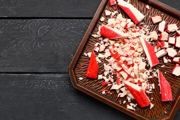 Plate with tasty cut crab sticks on dark wooden background, closeup © Pixel-Shot