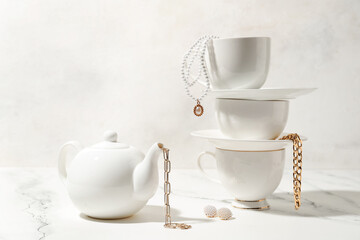 Tea set with stylish jewelry on white table
