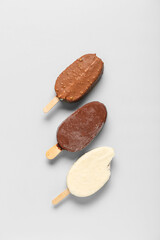Different chocolate covered ice cream on light background
