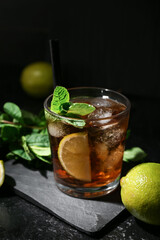 Glass of tasty Cuba Libre cocktail on dark background