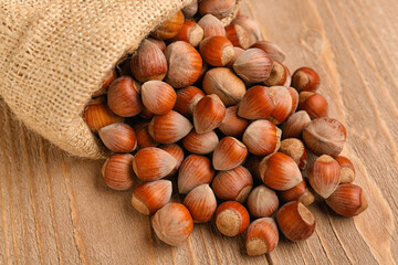 Sack bag with shelled hazelnuts on wooden background