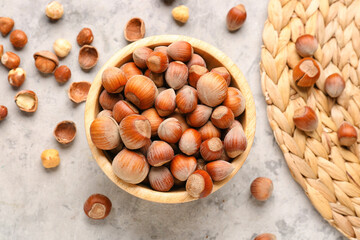 Bowl with shelled hazelnuts on grey grunge background
