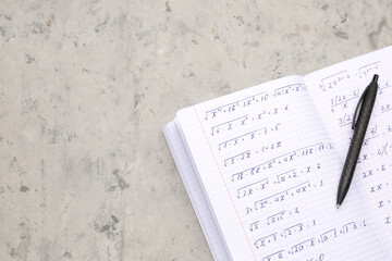 Copybook with maths formulas and pen on grey grunge background
