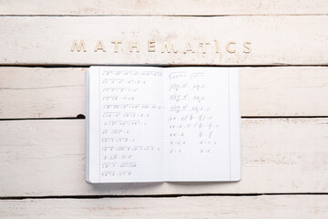 Naklejka premium Copybook with formulas and text MATHEMATICS on white wooden background