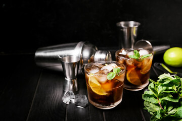Glasses of cold Cuba Libre cocktail on dark background