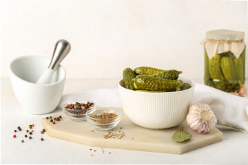 Mortar and board with bowl of canned cucumbers on white table