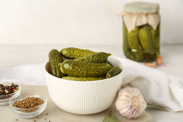 Board with bowl of canned cucumbers and ingredients on white table