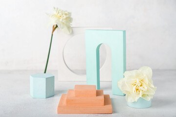 Decorative plaster podiums with daffodils on table against white wall