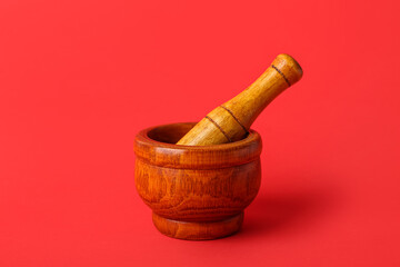 Wooden mortar and pestle on red background