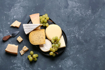 Different types of cheese with grapes on blue background