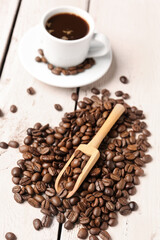 Scoop and coffee beans on light wooden background
