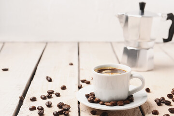 Cup of coffee and beans on light wooden table