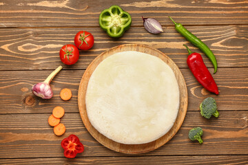 Board with raw dough and ingredients for preparing vegetable pie on wooden background