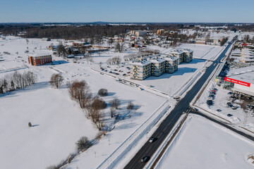 An aerial view of a city during winter, surrounded by built structures and skiing pistes covered in snow from the high angle viewpoint