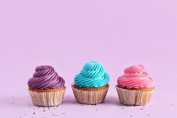 Tasty colorful cupcakes on purple background
