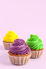 Tasty colorful cupcakes on purple background