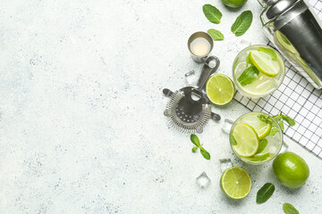 Glasses of tasty mojito and ingredients on light background