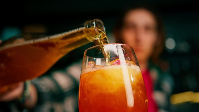 Preparation of Aperol Spritz cocktail bartender pouring prosecco into a glass with ice at the bar close-up