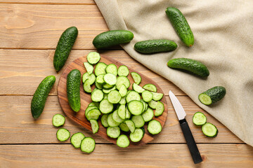 Board with fresh cut cucumbers on wooden background