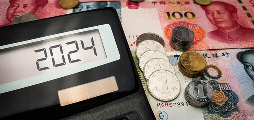 Conceptual image of the new fiscal year 2024 in China, depicting the country's economy and currency. Calculator displays the number 2024, while yuan notes and coins are seen in the background