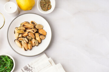 Plate with pickled mussels and bowl of seaweed salad on white background