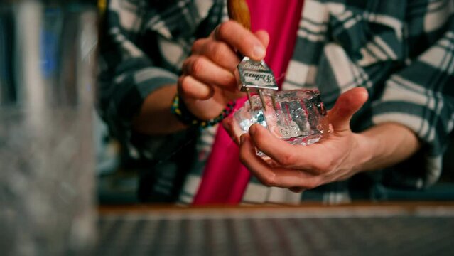 The bartender breaks the ice Close-up of male hands cracking ice with a sharp tool in a bar