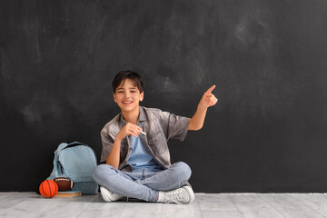 Little boy pointing at something near blackboard. Children's Day celebration